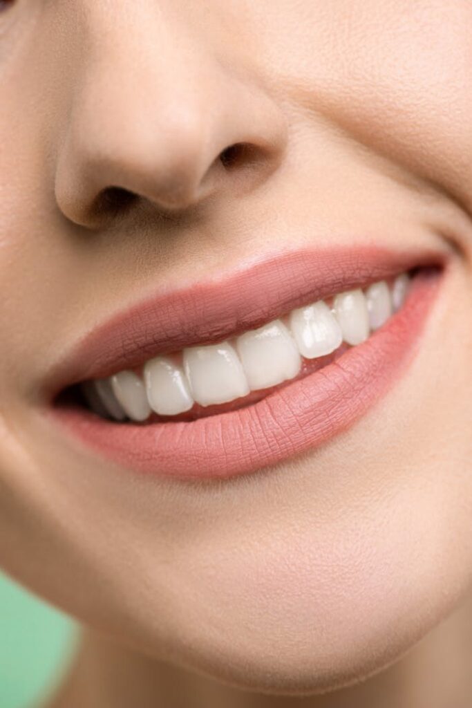 pexels photo 3762441 A close-up image focusing on a woman's smiling mouth, showing white teeth and pink lips.